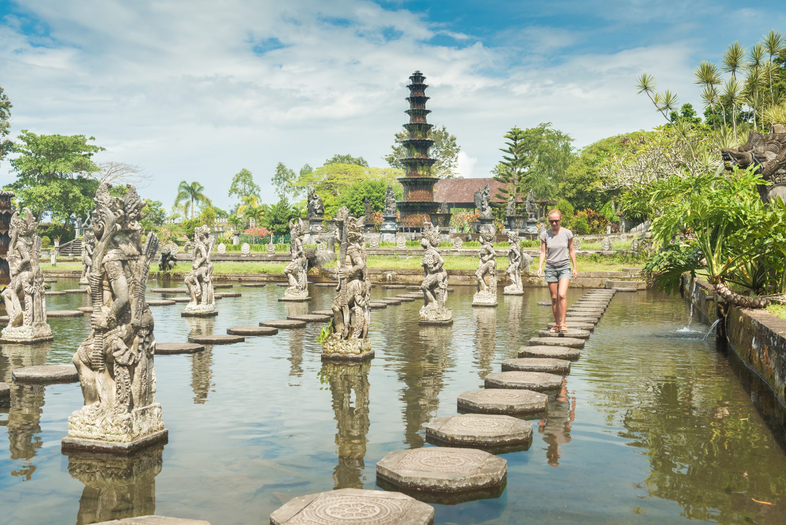 Happy tourist at Tirtagangga water palace with fountains and ponds on Bali, Indonesia